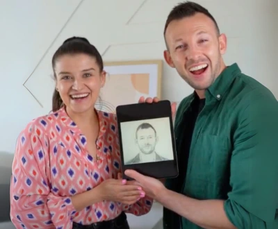 Joyful couple celebrating with Eva Bloom soulmate sketch displayed on tablet