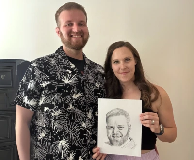 Couple smiling and holding hand-drawn soulmate portrait from Eva Bloom